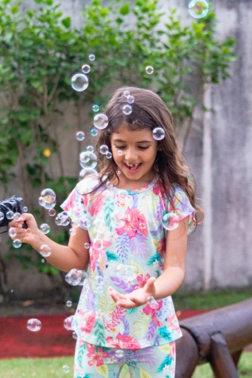 Garota brincando com máquina de bolhas de sabão em sua festa.