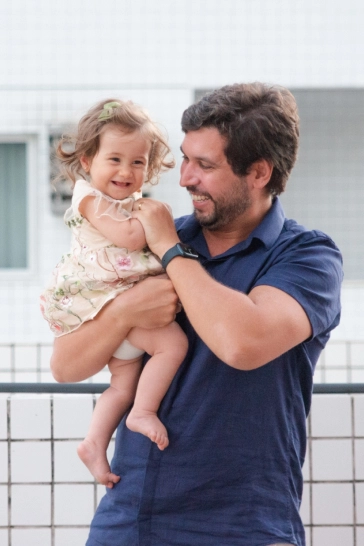 Clara nos braços do seu pai, ambos com um grande sorriso no rosto.