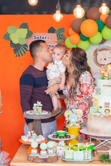 Na mesa do bolo, Guilherme recebe um cainhoroso beijo de seus pais, um em cada bochecha.