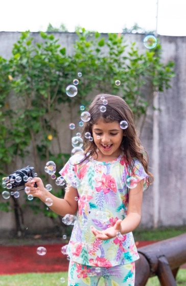 Sofia na área externa da festa brincando com a máquina de bolhas de sabão.